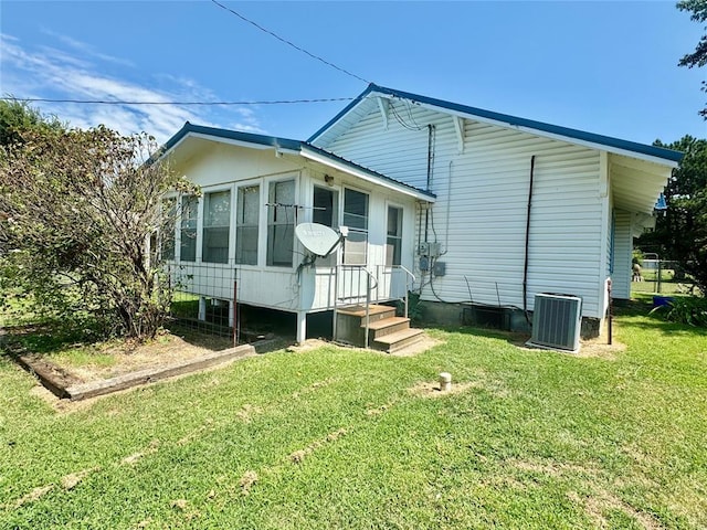 rear view of house featuring a lawn and central air condition unit