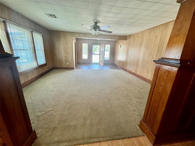 interior space featuring light carpet, ceiling fan, and wooden walls