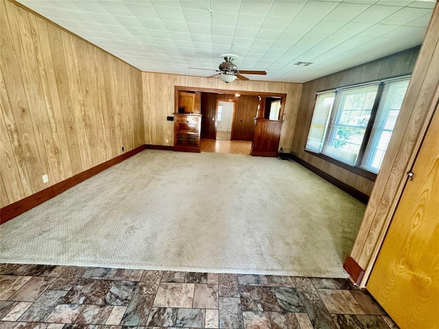 carpeted spare room featuring ceiling fan and wooden walls