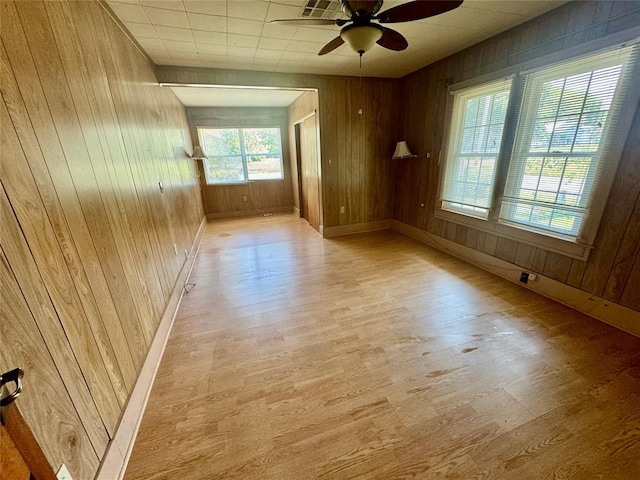 spare room with light hardwood / wood-style flooring, ceiling fan, and wooden walls