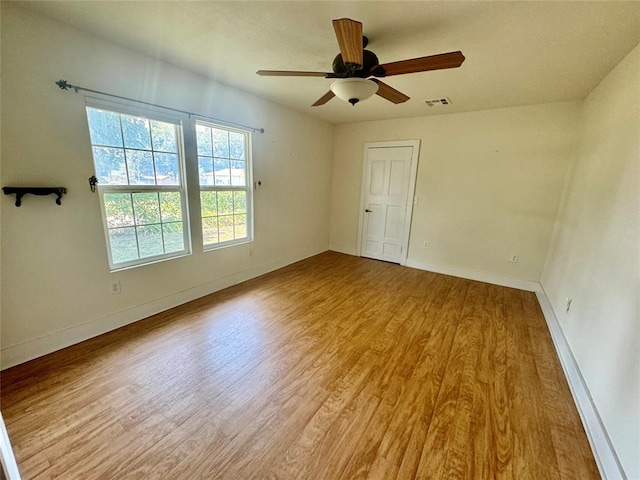 empty room with ceiling fan and light hardwood / wood-style flooring