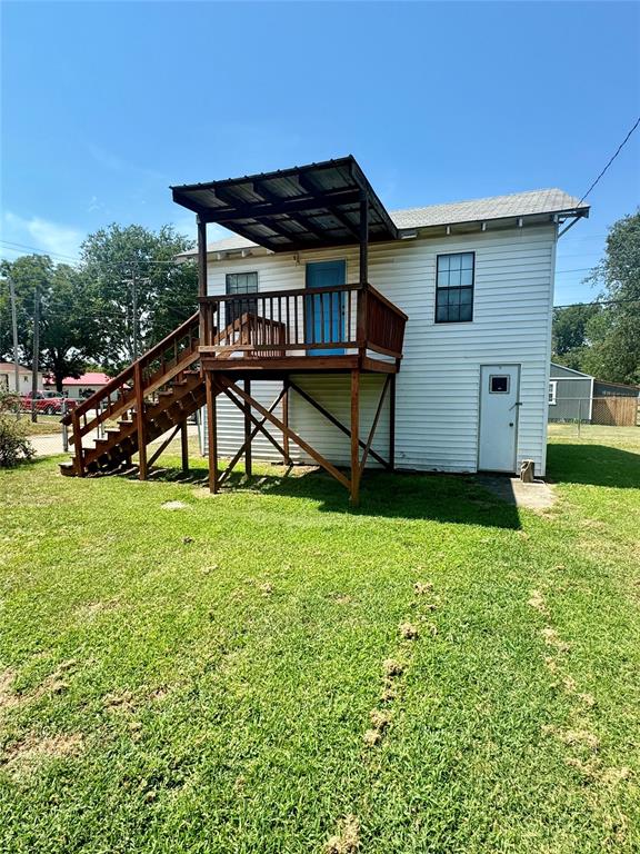 rear view of house with a lawn and a wooden deck