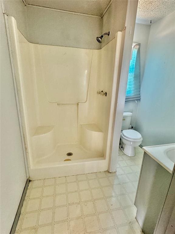 bathroom featuring a shower, a textured ceiling, and toilet