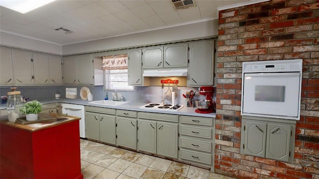 kitchen with white appliances, crown molding, and sink