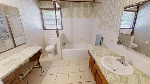 bathroom with vanity, tile patterned flooring, toilet, a tub to relax in, and tile walls