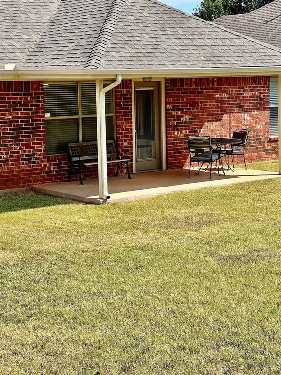 rear view of property featuring a lawn and a patio area