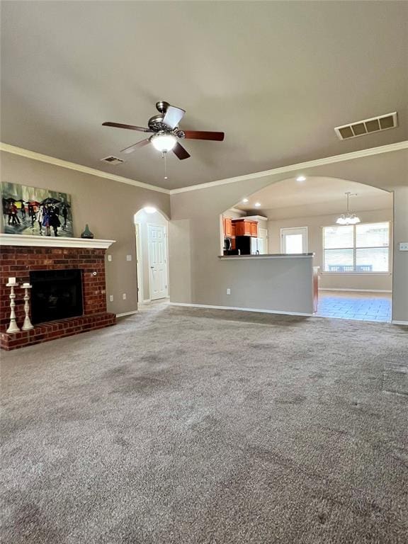 unfurnished living room featuring crown molding, a fireplace, carpet, and ceiling fan with notable chandelier