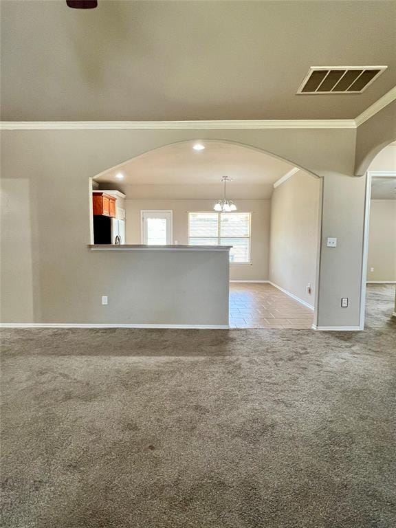 carpeted empty room featuring a notable chandelier and crown molding