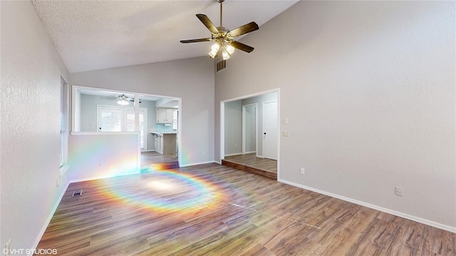 unfurnished living room with a textured ceiling, hardwood / wood-style flooring, and high vaulted ceiling