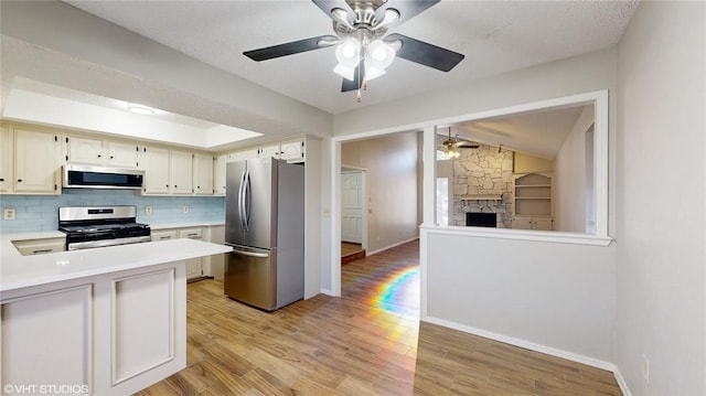 kitchen with kitchen peninsula, light wood-type flooring, stainless steel appliances, and lofted ceiling