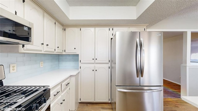 kitchen with stainless steel appliances, light hardwood / wood-style flooring, and white cabinetry