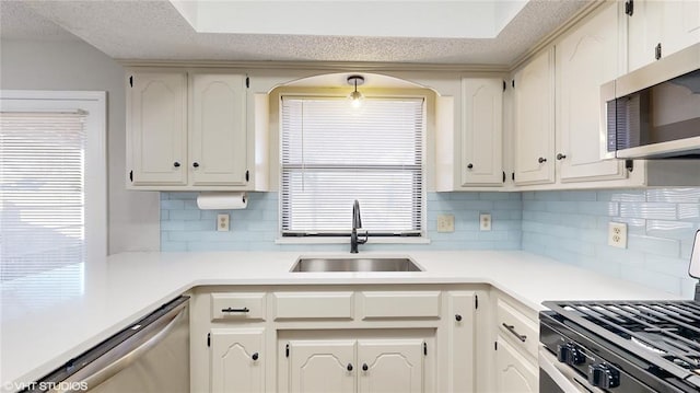 kitchen featuring decorative backsplash, appliances with stainless steel finishes, white cabinets, and sink