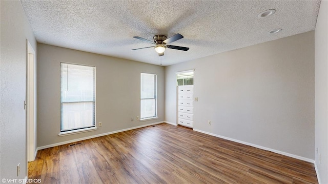 empty room featuring ceiling fan, hardwood / wood-style floors, and a textured ceiling