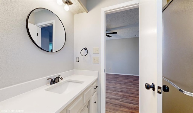 bathroom featuring hardwood / wood-style floors, vanity, ceiling fan, and a textured ceiling