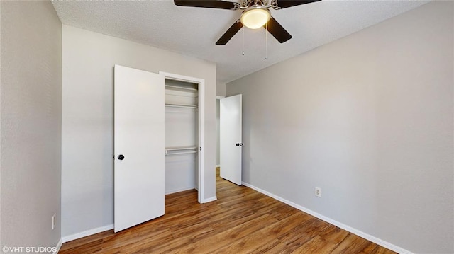 unfurnished bedroom with ceiling fan, a closet, a textured ceiling, and light hardwood / wood-style flooring