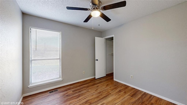 empty room featuring wood-type flooring, a textured ceiling, and ceiling fan