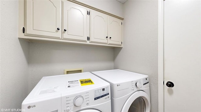 clothes washing area with cabinets and washing machine and dryer