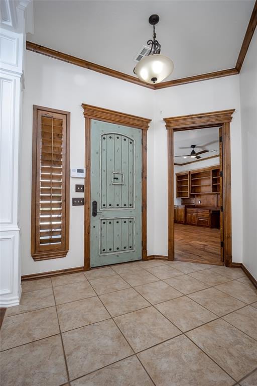 tiled entryway featuring crown molding and ceiling fan