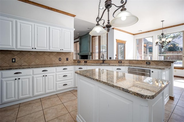 kitchen featuring a center island, backsplash, white cabinets, sink, and hanging light fixtures