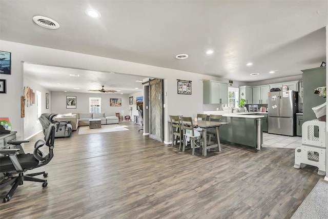 208 S Mockingbird Dr, Altus, OK 73521 - kitchen with freestanding refrigerator, a peninsula, light wood-type flooring, a kitchen breakfast bar, and light countertops