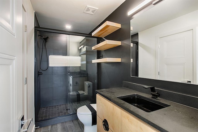 bathroom with a shower with door, vanity, and toilet