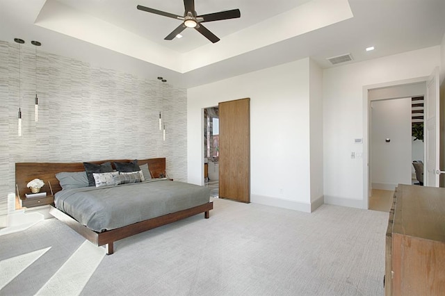 carpeted bedroom featuring ceiling fan and a raised ceiling