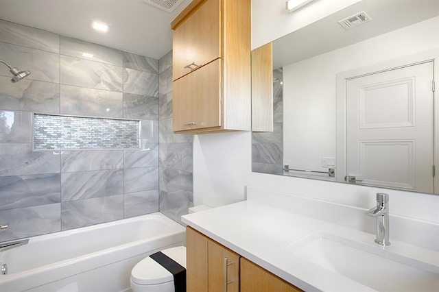 full bathroom featuring vanity, tiled shower / bath combo, and toilet