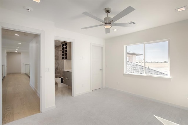 unfurnished bedroom featuring light carpet, a closet, ceiling fan, and ensuite bathroom