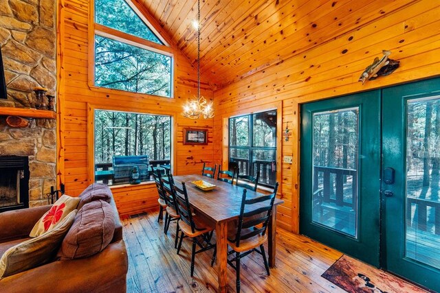 dining space with wood walls, a healthy amount of sunlight, high vaulted ceiling, and light hardwood / wood-style flooring