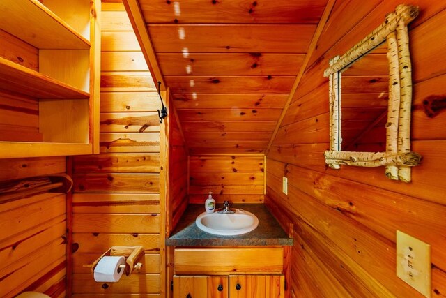 bathroom with vanity, vaulted ceiling, wood ceiling, and wood walls