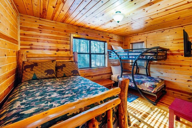 bedroom with hardwood / wood-style floors, wooden ceiling, and wooden walls