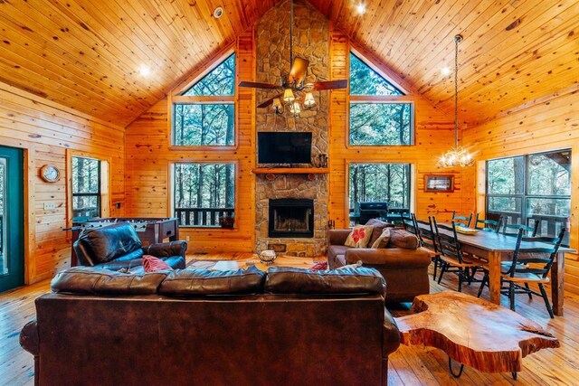 living room featuring wood walls, a fireplace, high vaulted ceiling, and light hardwood / wood-style flooring