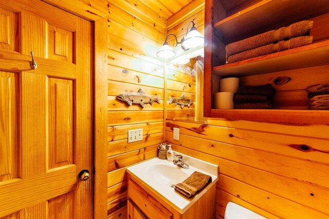 bathroom featuring vanity, wood walls, and toilet