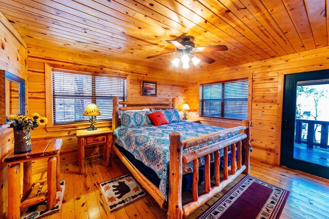 bedroom featuring ceiling fan, wood walls, light wood-type flooring, and multiple windows