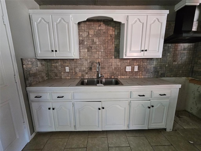 kitchen with white cabinets, wall chimney exhaust hood, backsplash, and sink