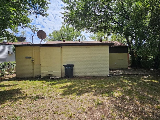 rear view of property featuring a lawn and a wall mounted air conditioner