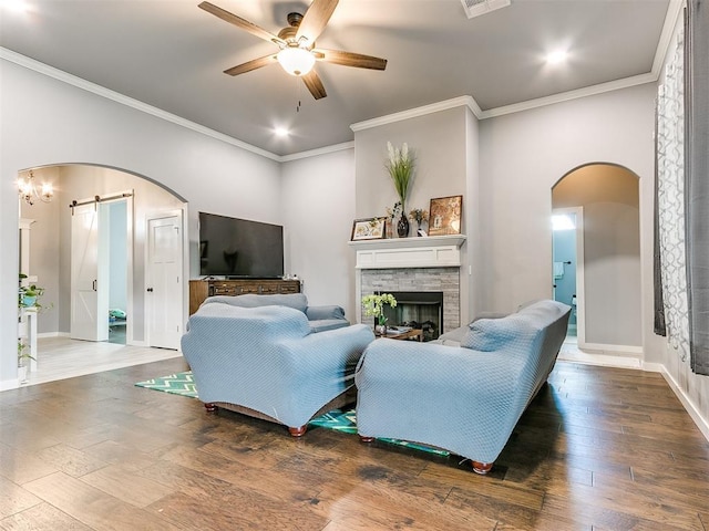 1301 Atalon Dr, Moore, OK 73160 - living room with a barn door, arched walkways, ceiling fan, crown molding, and hardwood / wood-style floors