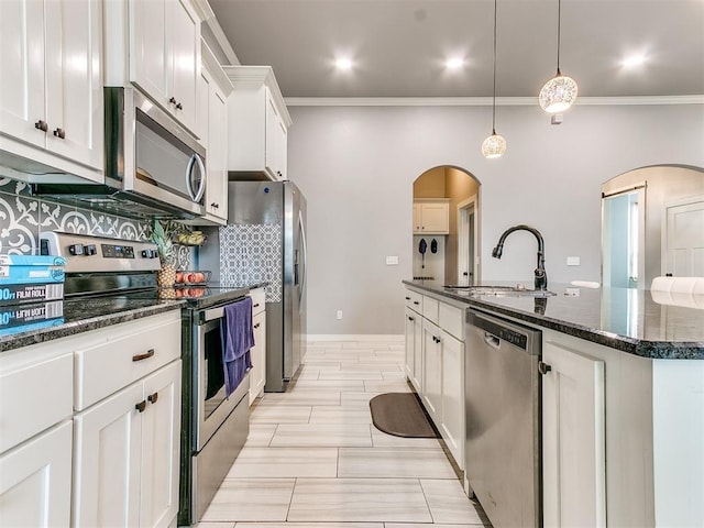 1301 Atalon Dr, Moore, OK 73160 - kitchen featuring stainless steel appliances, arched walkways, ornamental molding, a center island with sink, and white cabinetry