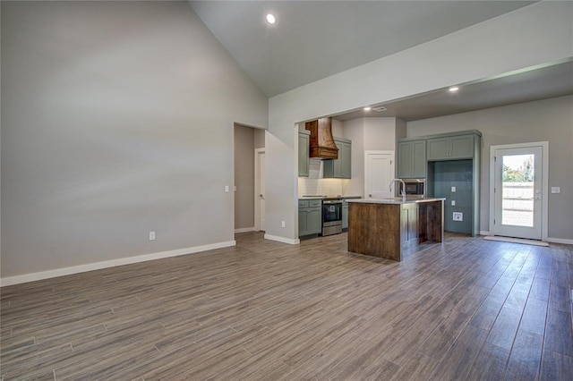 kitchen with stainless steel range, hardwood / wood-style floors, a kitchen island with sink, and custom exhaust hood