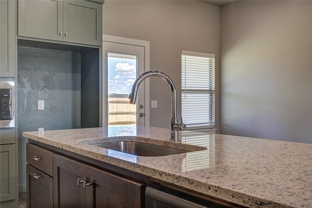 kitchen with light stone countertops, plenty of natural light, dishwasher, and sink