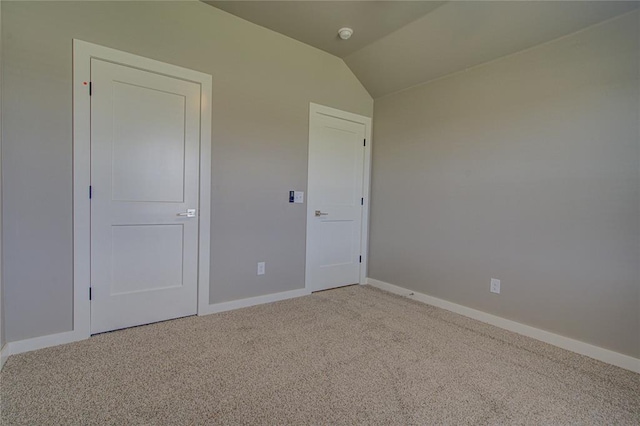 unfurnished bedroom with light carpet, a closet, and vaulted ceiling