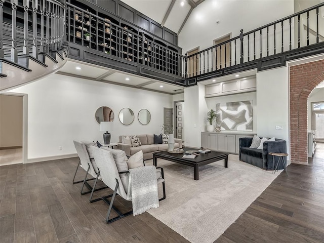 living room with a towering ceiling and dark wood-type flooring