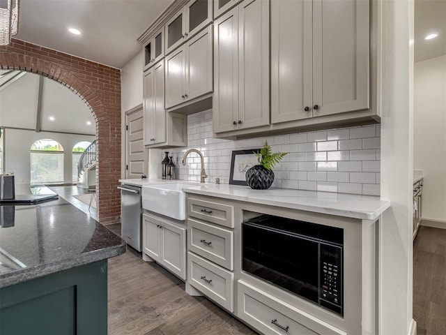 kitchen featuring dishwasher, sink, dark hardwood / wood-style floors, light stone countertops, and black microwave