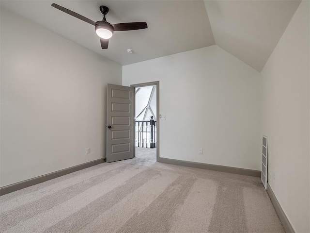 spare room featuring ceiling fan, light colored carpet, and vaulted ceiling