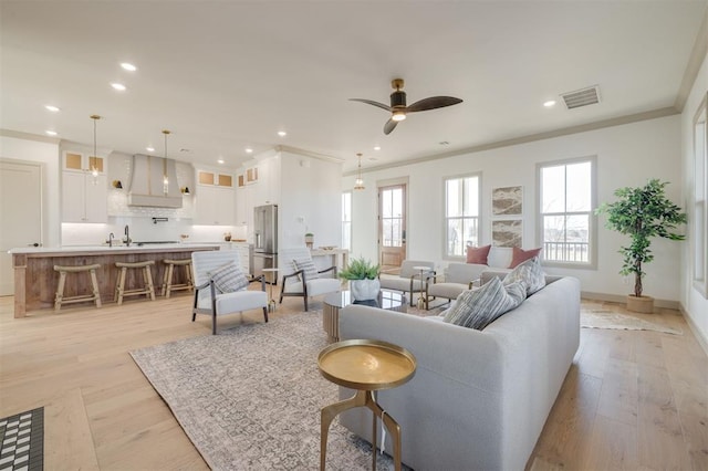 living room with light hardwood / wood-style flooring, ceiling fan, and crown molding