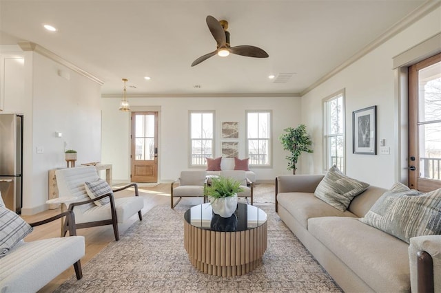 living room with a wealth of natural light, crown molding, and light hardwood / wood-style floors