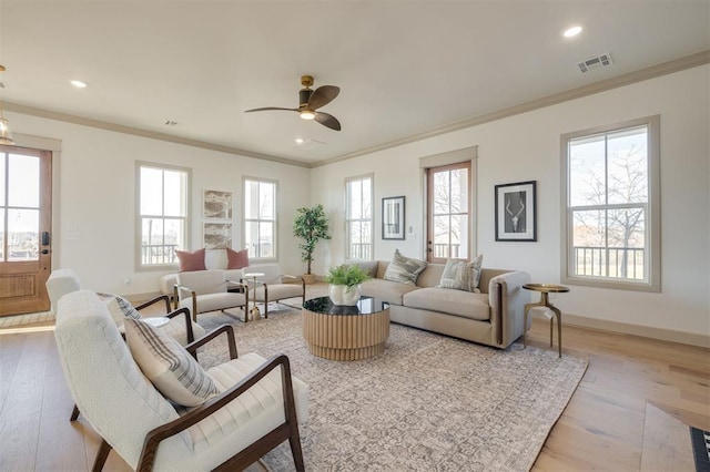 living room with plenty of natural light, light hardwood / wood-style floors, ornamental molding, and ceiling fan