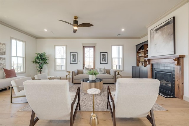 living room featuring a fireplace, ceiling fan, light hardwood / wood-style flooring, and ornamental molding