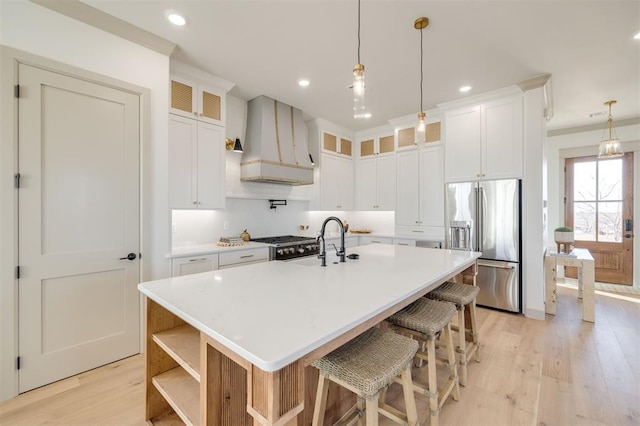 kitchen featuring a center island with sink, white cabinets, custom exhaust hood, and appliances with stainless steel finishes