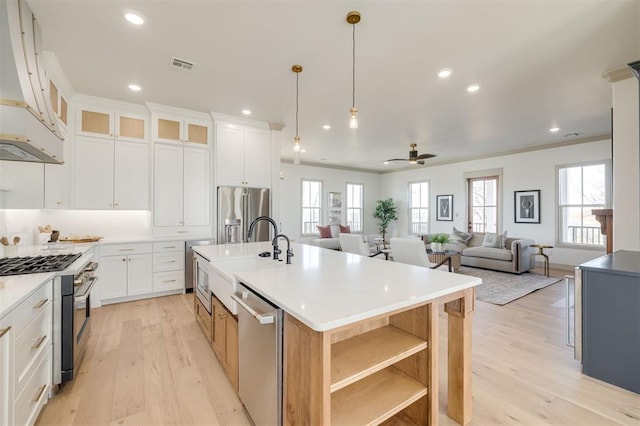 kitchen with premium appliances, a center island with sink, white cabinetry, and ceiling fan